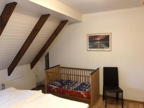 a bedroom with a crib and a chair in it at Marbijes Appartementhaus in Cuxhaven