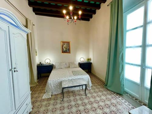 1 dormitorio con cama y lámpara de araña en GINVA - Casa palacio La Templanza, en El Puerto de Santa María
