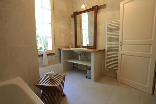 a bathroom with a sink and a mirror and a tub at Maison Dans Le Parc Du Château in Larçay