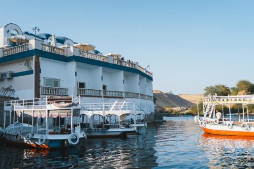two boats are docked next to a building on the water at NUB INN in Aswan