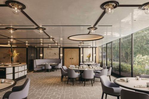 a dining room with tables and chairs and large windows at Conrad Singapore Orchard in Singapore