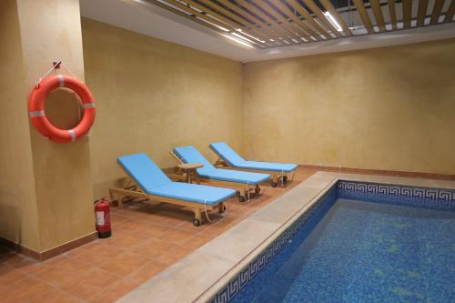 una piscina con sillas azules y un salvavidas rojo en Dar Hashim Hotel Suites - Alnuzha en Riad