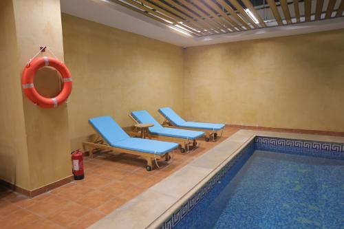 a swimming pool with blue chairs and a red life preserver at Dar Hashim Hotel Suites - Alnuzha in Riyadh