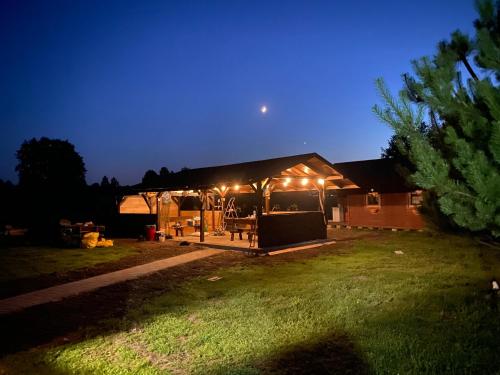 uma casa com um gazebo iluminado à noite em Przystań Stare Kotlice 