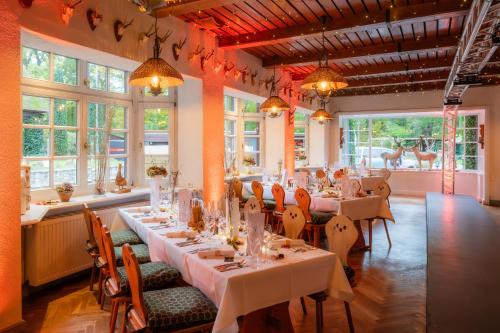 uma sala de jantar com mesas, cadeiras e janelas em Hotel Forsthaus Damerow em Ostseebad Koserow