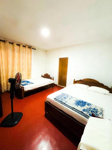 Rattota的住宿－Knuckles bungalow，一间设有两张床的卧室,铺有红色地板