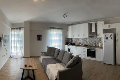een woonkamer met een bank en een keuken bij Lovely apartment 2’ walking from Anavyssos beach in Anavissos