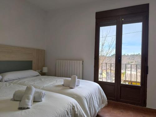 a bedroom with two beds and a window with a view at Masia Del Cura in Rubielos de Mora