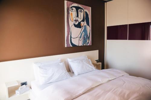 een slaapkamer met een wit bed en een schilderij aan de muur bij Park View Apartment in Tirana