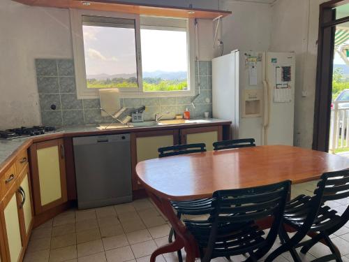 cocina con mesa de madera y nevera en CosyLife Sainte-Rose - Villa calme avec vue Sofaïa à 3km de la plage en Sainte-Rose