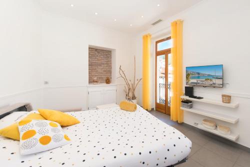 - une chambre avec un lit doté d'oreillers jaunes et une télévision dans l'établissement MARNE III - SPACIEUX 3-4 PIÈCES - Carré d'Or Menton, à Menton