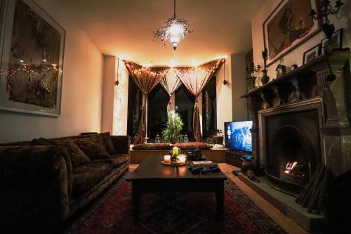 uma sala de estar com um sofá, uma mesa e uma televisão em Crow Nest House em Hebden Bridge