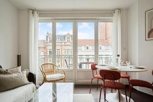 - un salon avec une table, des chaises et une grande fenêtre dans l'établissement Lille hypercentre two bedrooms 70m2, à Lille