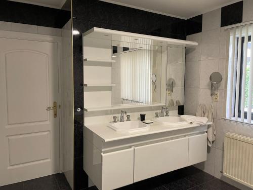 Baño blanco con 2 lavabos y espejo en Vakantiewoning Villa 35, en Maasmechelen