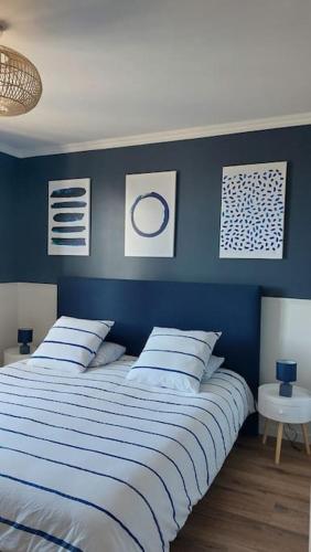 a bedroom with a blue wall with a bed with pillows at La Picotterie in Portbail