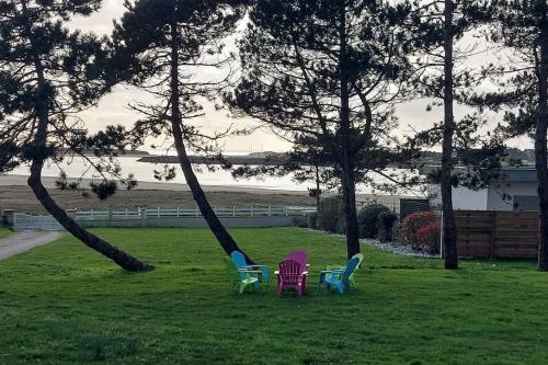 three chairs sitting in the grass next to trees at La Picotterie in Portbail