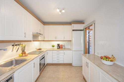 a kitchen with white cabinets and a bowl of fruit on the counter at Can Bennasar in Can Picafort