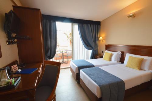 a hotel room with two beds and a window at Hotel Montecarlo in Rome