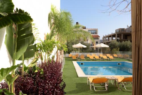 uma piscina num quintal com cadeiras e guarda-sóis em Sergios Hotel em Hersonissos