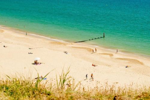 a group of people on a beach near the ocean at Beach Walk Southbourne SOBO Beach Sleeps 4 in Southbourne
