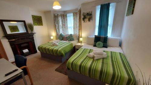 a small room with two beds and a fireplace at Cosy Villa- 5 Bedroom Accommodation Great For Longer Stays!!! in Chatham