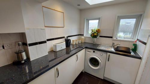 a kitchen with a sink and a washing machine at Cosy Villa- 5 Bedroom Accommodation Great For Longer Stays!!! in Chatham