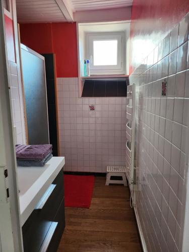 - une petite salle de bains avec des murs rouges et du carrelage blanc dans l'établissement la chambre d'Axelle, à La Bachellerie