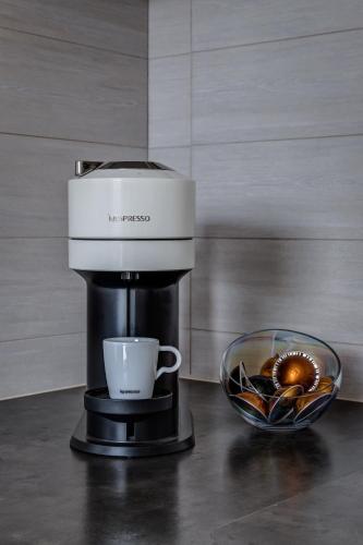 a coffee maker with a cup and a bowl of nuts at Wellness apartmány Český ráj & Biokolna in Lomnice nad Popelkou