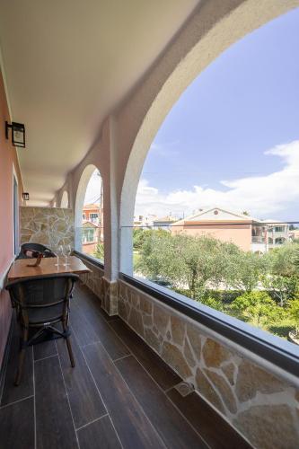 a balcony with a table and a large window at Mathraki Resort in Gouvia