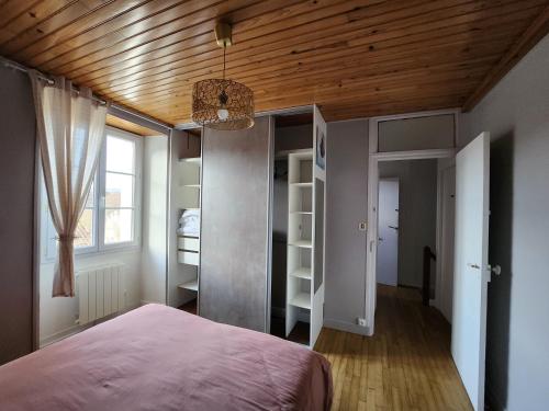 une chambre avec un lit et un plafond en bois dans l'établissement la chambre d'Axelle, à La Bachellerie