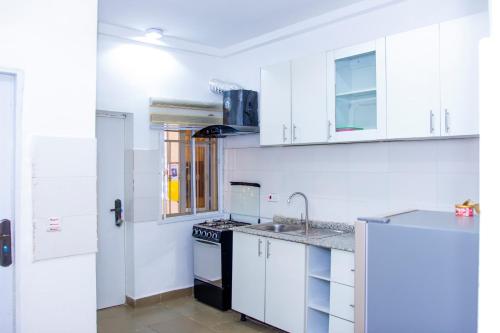 uma cozinha com armários brancos e um lavatório em Marathona Service Apartments em Abuja