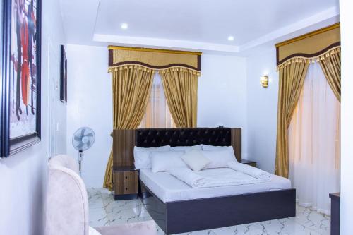 um quarto com uma cama grande e cortinas amarelas em Marathona Service Apartments em Abuja