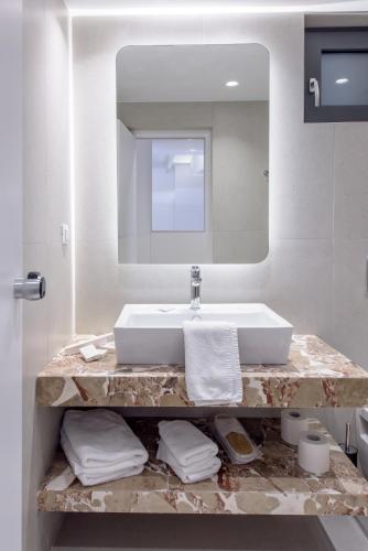 a bathroom with a sink and a mirror at Iraklion Hotel in Heraklio Town