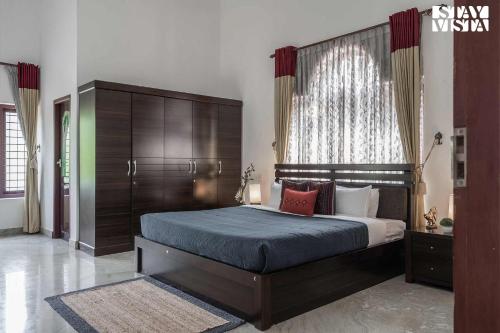 a bedroom with a large bed with a wooden headboard at StayVista at Periyar Palace- Pet Friendly, River View Villa with Garden in Cochin