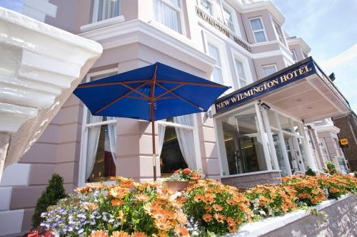 a blue umbrella in front of a building with flowers at New Wilmington Hotel in Eastbourne
