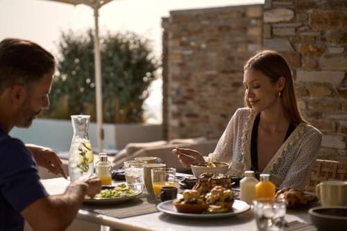 a man and woman sitting at a table eating food at Ios Grand Pool Suites in Mylopotas