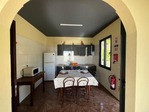 een keuken met een tafel met stoelen en een koelkast bij Fernanda's House in Ribeira Brava
