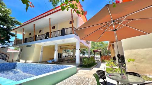 a house with a swimming pool and an umbrella at M Y hotel in Dili