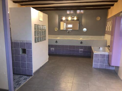 La salle de bains est pourvue de carrelage bleu, d'un lavabo et d'un miroir. dans l'établissement Entre champs et forêt, à Allouis