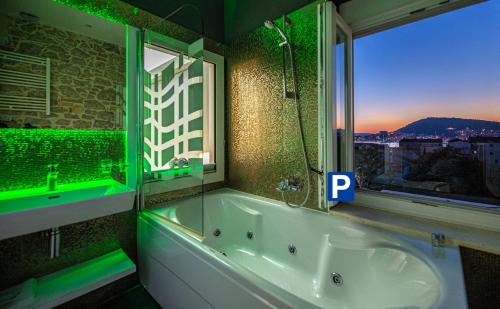a bathroom with a tub and a window with green lights at A Heritage Split in Split