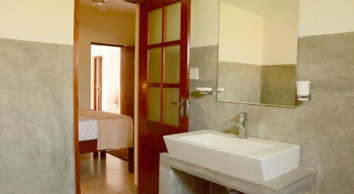 baño con lavabo, espejo y cama en Inlak Garden Hotel en Negombo