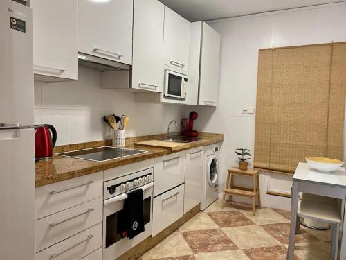 a kitchen with white cabinets and a sink and a stove at Casa encantadora y confortable en Málaga. in Málaga