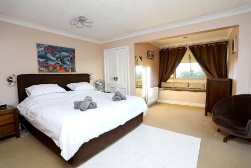 una camera da letto con un grande letto con due peluche sopra di Picturesque Family Hideaway Chipping Ongar Essex a Fyfield