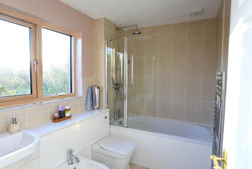 uma casa de banho com uma banheira, um WC e um lavatório. em Picturesque Family Hideaway Chipping Ongar Essex em Fyfield