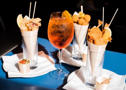 a table topped with four glasses of food and snacks at Babila Hostel & Bistrot in Milan