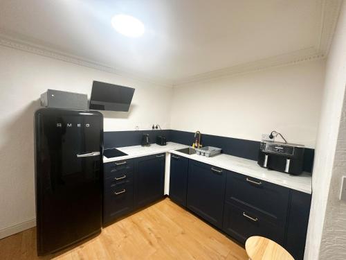 a kitchen with black cabinets and a black refrigerator at Flat 4, Stay in Aldgate in London
