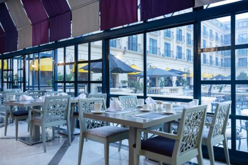a restaurant with white tables and chairs and windows at Concorde El Salam Cairo Hotel & Casino in Cairo