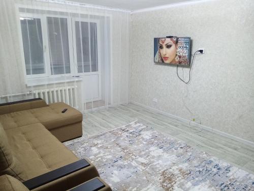 sala de estar con sofá y una foto en la pared en 3 комнатная квартира, en Uralsk