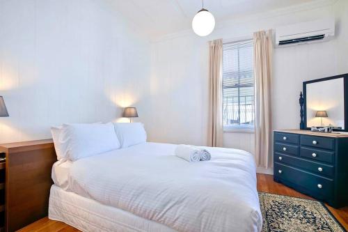 a bedroom with a white bed and a blue dresser at Charming heritage house in the heart of the city in Brisbane