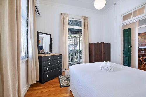 a bedroom with a bed and a dresser and a window at Charming heritage house in the heart of the city in Brisbane